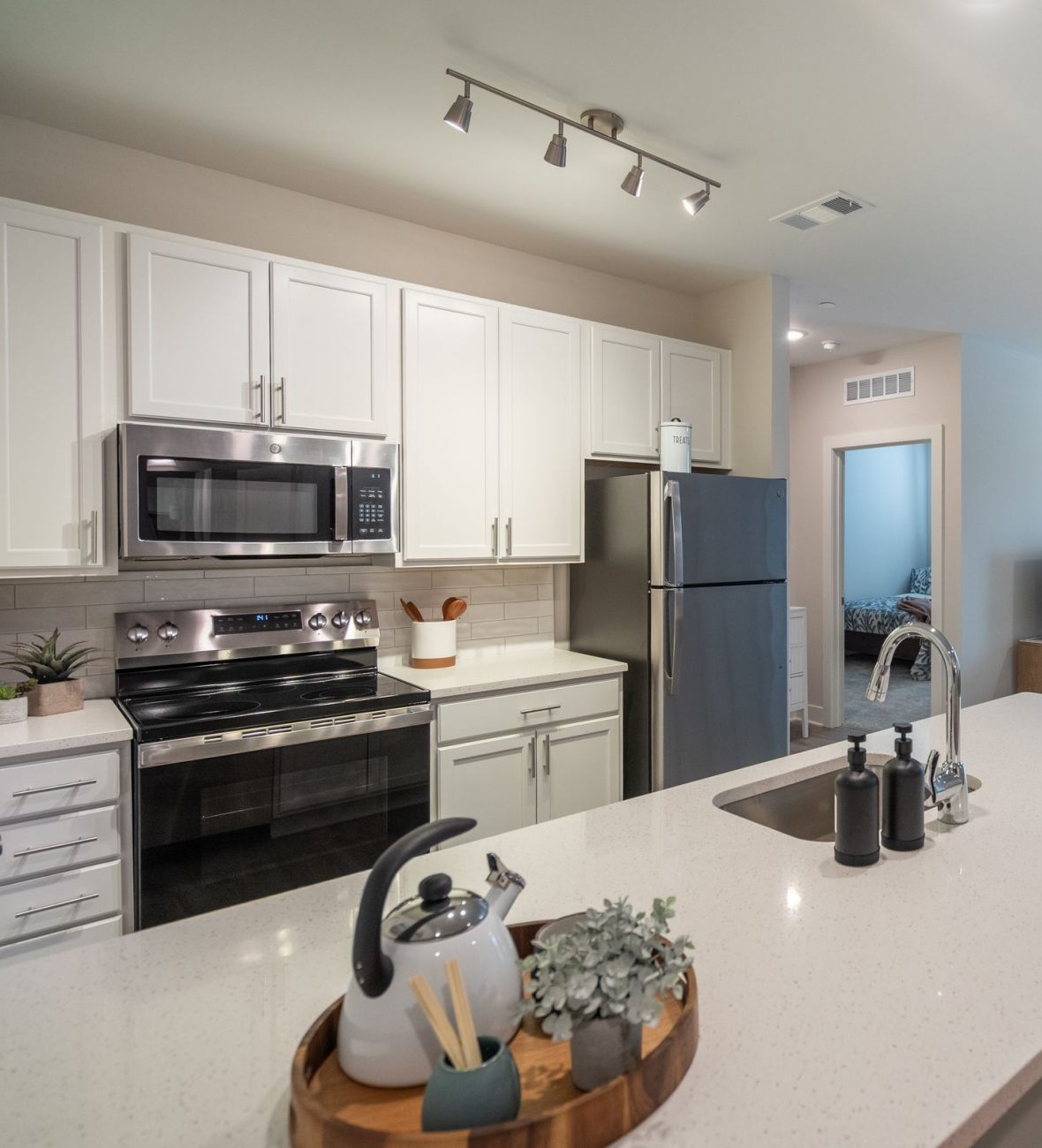 Acclaim at Greenbrier  apartment homes with Modern open kitchen with white cabinets, stainless appliances, and a view into a bright living room.