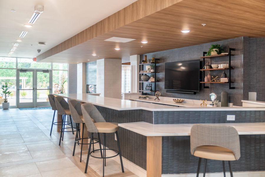 Acclaim at Greenbrier  apartment homes with Modern lounge area with bar seating, a large TV, open shelves, and floor-to-ceiling windows.