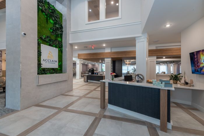Acclaim at Greenbrier apartment homes with Modern lobby with a front desk, green wall decor, and contemporary furnishings in a well-lit space.