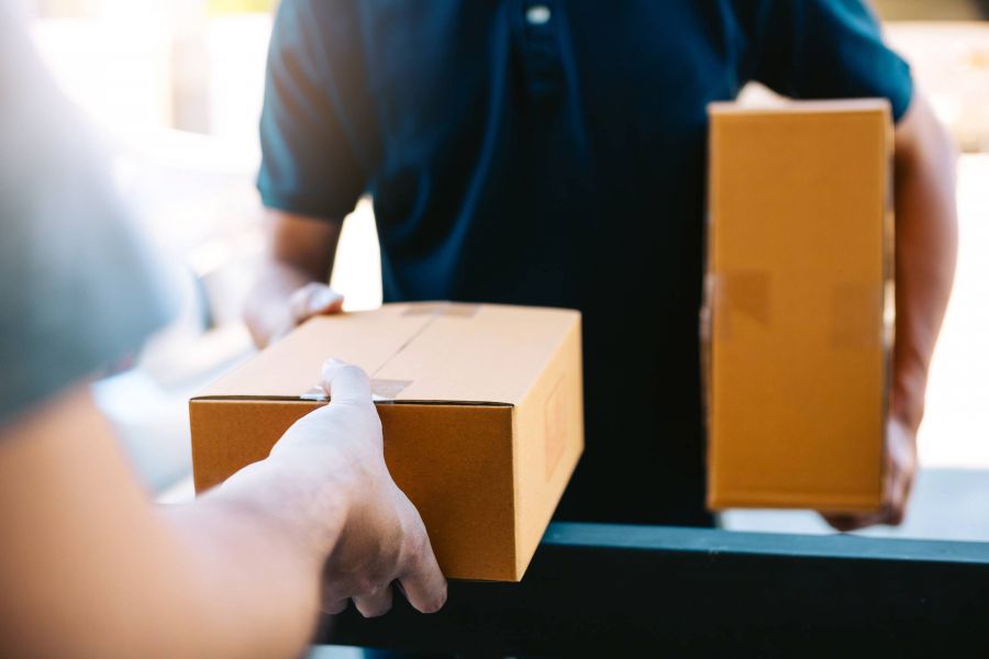 Acclaim at Greenbrier apartment homes with Person handing a cardboard box to another person holding a package, likely during a delivery.