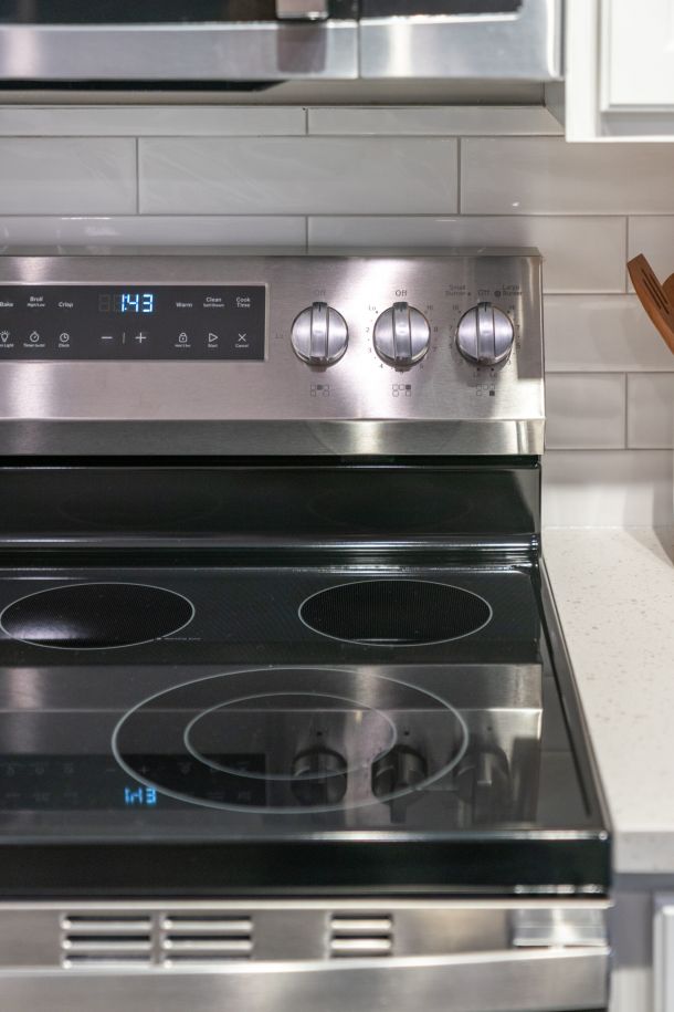 Acclaim at Greenbrier apartment homes with A modern electric stove with digital controls and four burners, set against a white tile backsplash.